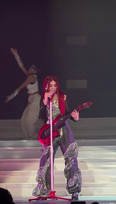 lady with red hair on stage playing guitar