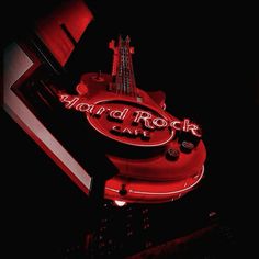 a red neon sign that says hard rock cafe on it's side in the dark