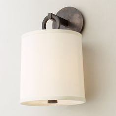 a wall light with a white shade hanging from it's side on the wall