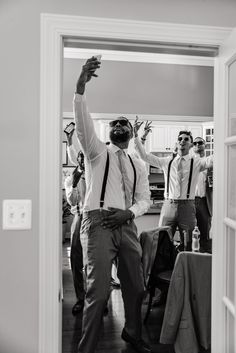 a group of men standing around each other in front of a doorway with their arms up