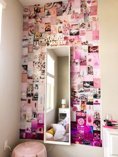 a mirror sitting on top of a white dresser next to a wall covered in pictures