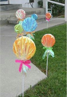 some colorful candy lollipops sitting in the grass on top of a sidewalk