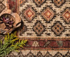 a vase with flowers on top of a rug next to a flower potted plant