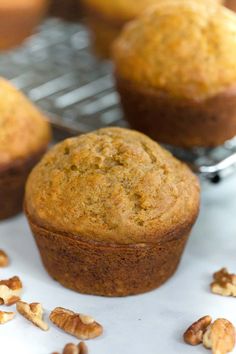 several muffins sitting on top of a cooling rack with walnuts around them