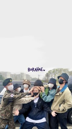 a group of people wearing face masks and standing in front of a car with the word borahale written on it