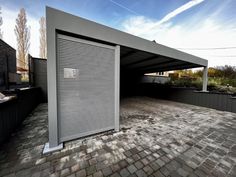 an open garage door on the side of a brick road with trees in the background