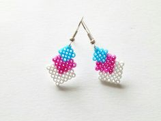 the earrings are made out of beads and have pink, blue, and white designs on them