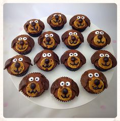 cupcakes with chocolate frosting and decorated like dogs on a white platter