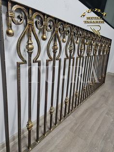 an ornate iron railing with brass finial and handrails on the side of a white wall