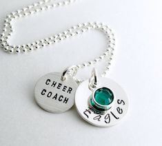 two necklaces with names on them sitting on a white table next to a ball chain