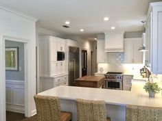 a kitchen with white cabinets and an island in the middle is seen from across the room