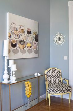 a chair and table in a room with blue walls, yellow accents and a painting on the wall