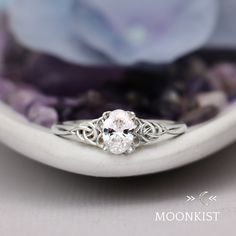 This dainty Oval Celtic Promise Ring features a sparkling 7 x 5 mm oval gemstone (approx. .75 cts.), shown here in lab-grown Moissanite. This ring features a secure, low-rise mounting. Decorative Celtic knots offer a beautiful counterpoint to the oval shaped stone. Includes Sterling Silver Celtic Mounting, Your Choice of 7 x 5 mm Faceted Oval Stone Dimensions - 7 mm at widest point, 2 mm at band. Stone sits 4.5 mm above the finger Includes Free Ring Sizing, One Year Warranty Delicate Oval Diamond White Rings, Delicate Oval Solitaire Jewelry, Oval Diamond White Wedding Gift, Delicate Oval Sterling Silver Rings, Delicate Oval White Diamond Ring, Delicate White Oval Diamond Ring, Delicate Oval Diamond Ring Gift, Dainty Oval Diamond Ring With Accent Stones, Dainty Oval White Gold Ring