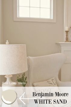 a living room with white furniture and a lamp on the side table in front of a window