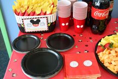 a mickey mouse themed birthday party with plates and cups, napkins and snacks on the table