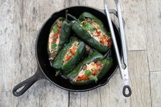 some green peppers are in a black pan with tongs on the table next to them