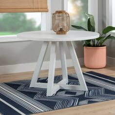 a white table sitting on top of a wooden floor next to a potted plant