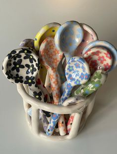 a basket filled with lots of colorful spoons sitting on top of a white table