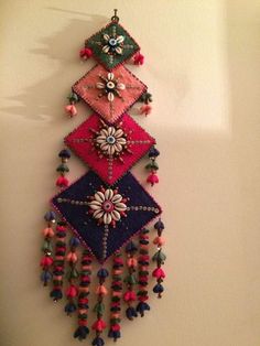 a multicolored beaded wall hanging on the wall next to a white wall