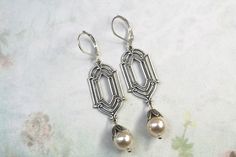 Silver Art Deco Earrings- Cream Pearl Dangle Earrings- Vintage Inspired- 1920's Earrings- Bridal Earrings- Coquette  Style- Cottagecore  Stunning art deco style earrings Hanging from a silver plated deco style connector are 8mm cream CRYSTAL pearls that have a silver bead cap  They are 2 1/4 inches long and 1/2 inch wide They suspend from silver plated lever back ear wires.  If you need a larger quantity please message me  They arrive in a gift box with a bow Thanks for looking, Lori 1920s Earrings, Earrings Hanging, Coquette Style, Deco Earrings, Pearl Cream, Art Deco Earrings, Silver Art, Pearl Earrings Dangle, Silver Bead