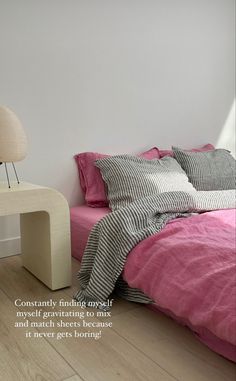 there is a bed with pink sheets and pillows