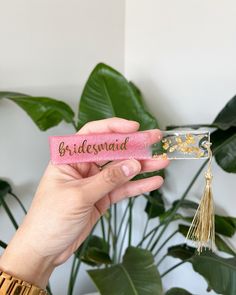 the bridesmaid name tag is held in front of a plant