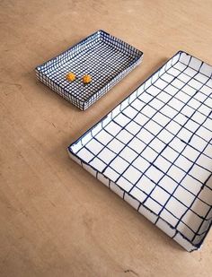 two blue and white trays sitting on top of a wooden table next to each other