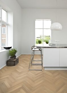 a kitchen with white walls and wooden floors has a bar stool next to the counter