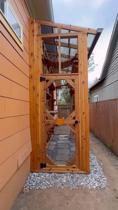 a wooden bird cage sitting on the side of a house