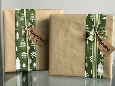 two wrapped gift bags sitting on top of a glass table with a tag that says happy holidays