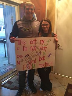 two people standing next to each other holding a sign