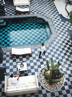 an aerial view of a pool and patio area with couches, tables, and chairs