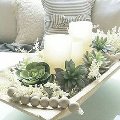 a tray filled with candles and succulents on top of a table