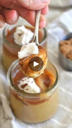 a person holding a spoon with some food in it on top of a glass jar