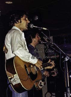 two men singing into microphones while playing guitars