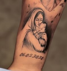 a woman holding a baby in her arms with the birth date tattooed on it's arm