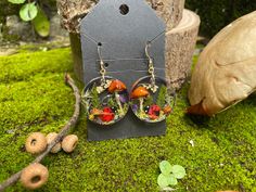 These exquisite handmade earrings are truly a one-of-a-kind piece of nature-inspired art. Crafted from resin and adorned with real mushrooms, pressed ferns, delicate flowers, tiny acorns, moss, and a charming ladybug, these earrings are a special gift for anyone who appreciates nature's beauty. Whether you're shopping for your teacher, best friend, daughter, mom, or girlfriend, they are sure to treasure these unique earrings. Give the gift of nature and style with these stunning and whimsical earrings. 💙 Beautiful and unique design 💙 natural materials (real mushrooms, moss and fern) 💙 Hypoallergenic sterling silver or gold filled hooks 💙 Both rubber & soft-close backs provided 💙Lightweight and comfortable 💙Entirely handmade MATERIALS. The earrings are made of UV resin, real dry mushr Whimsical Resin Jewelry With Ear Wire, Handmade Nature-inspired Resin Earrings, Nature-inspired Handmade Resin Earrings, Unique Mushroom Design Earrings As Gift, Unique Mushroom Design Earrings For Gift, Nature-inspired Dangle Earrings With Mushroom Design, Mushroom Design Dangle Earrings As Gift, Mushroom Design Dangle Earrings For Gift, Nature-inspired Dangle Jewelry With Mushroom Design