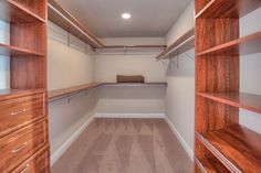 an empty walk in closet with wooden shelves