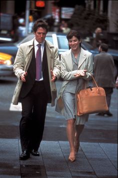 the man and woman are walking down the street holding hands with each other as they both carry bags