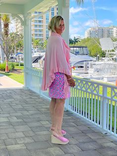 a woman in pink is standing on a porch