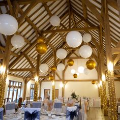 a room filled with lots of tables covered in white and blue cloths next to balloons