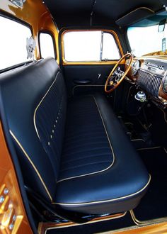 the interior of an old car with black leather seats and gold trimming on it