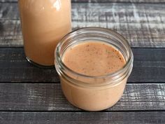 two jars filled with brown liquid sitting on top of a wooden table next to each other