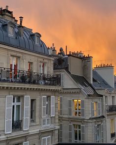 the sun is setting over some buildings in paris, with windows and balconies