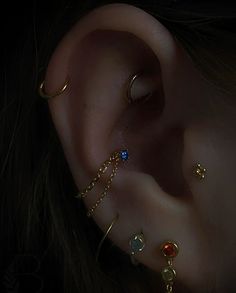 an ear with multiple piercings on it and two different colored stones in the middle