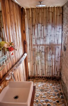 a bathroom with stone flooring and bamboo blinds on the window sill, along with a white sink