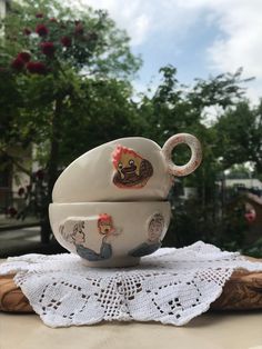 a white tea pot and saucer sitting on top of a doily