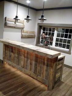 a large wooden counter sitting in the middle of a room next to two lights and a window