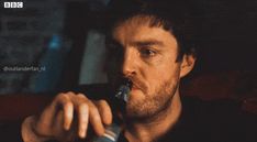 a man drinking from a bottle while sitting in a chair