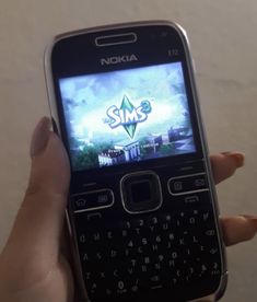 a person holding up a smart phone with the sims logo on it's screen